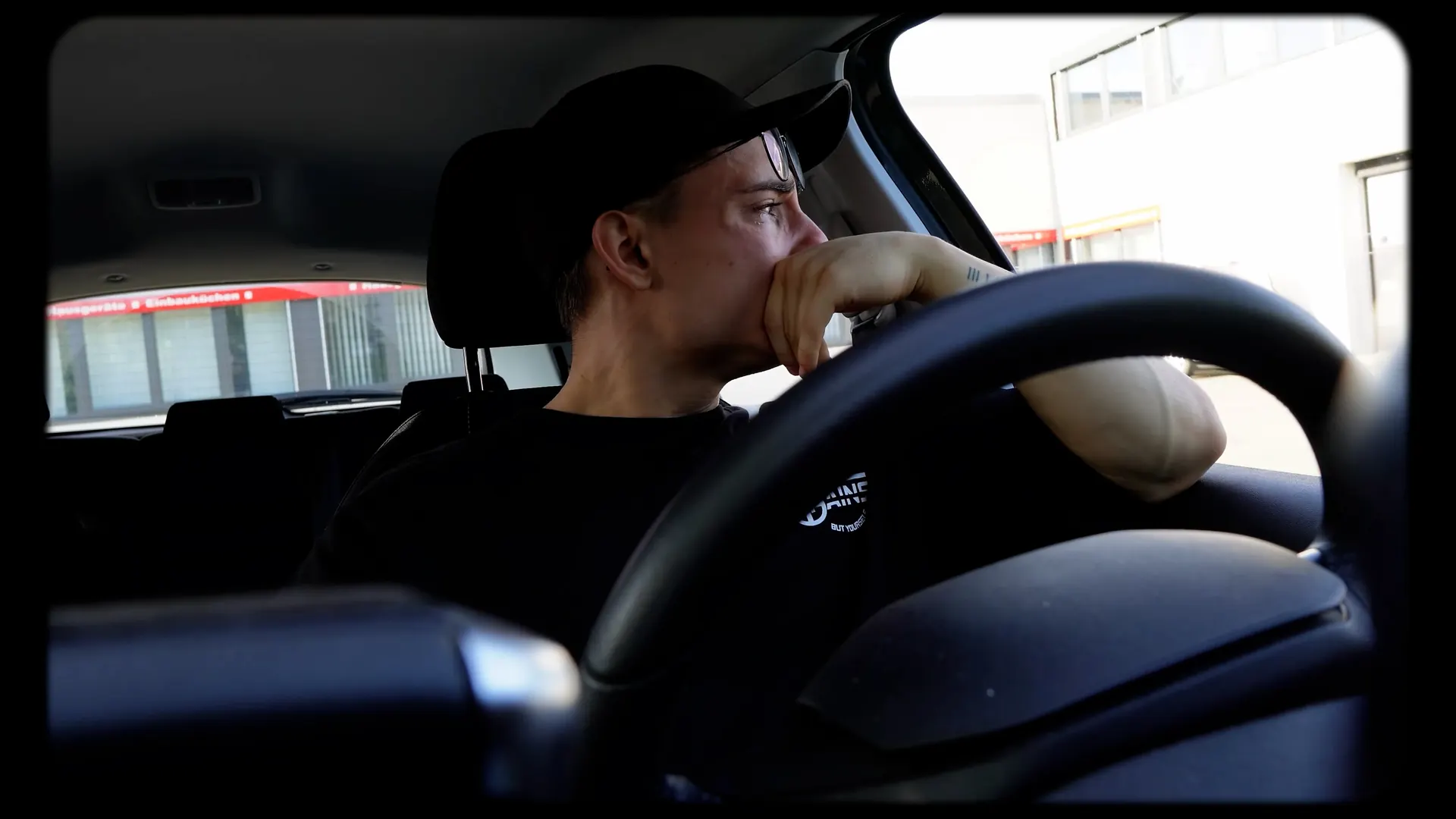 Fahrt im Auto, der Athlet mit Cap am Steuer