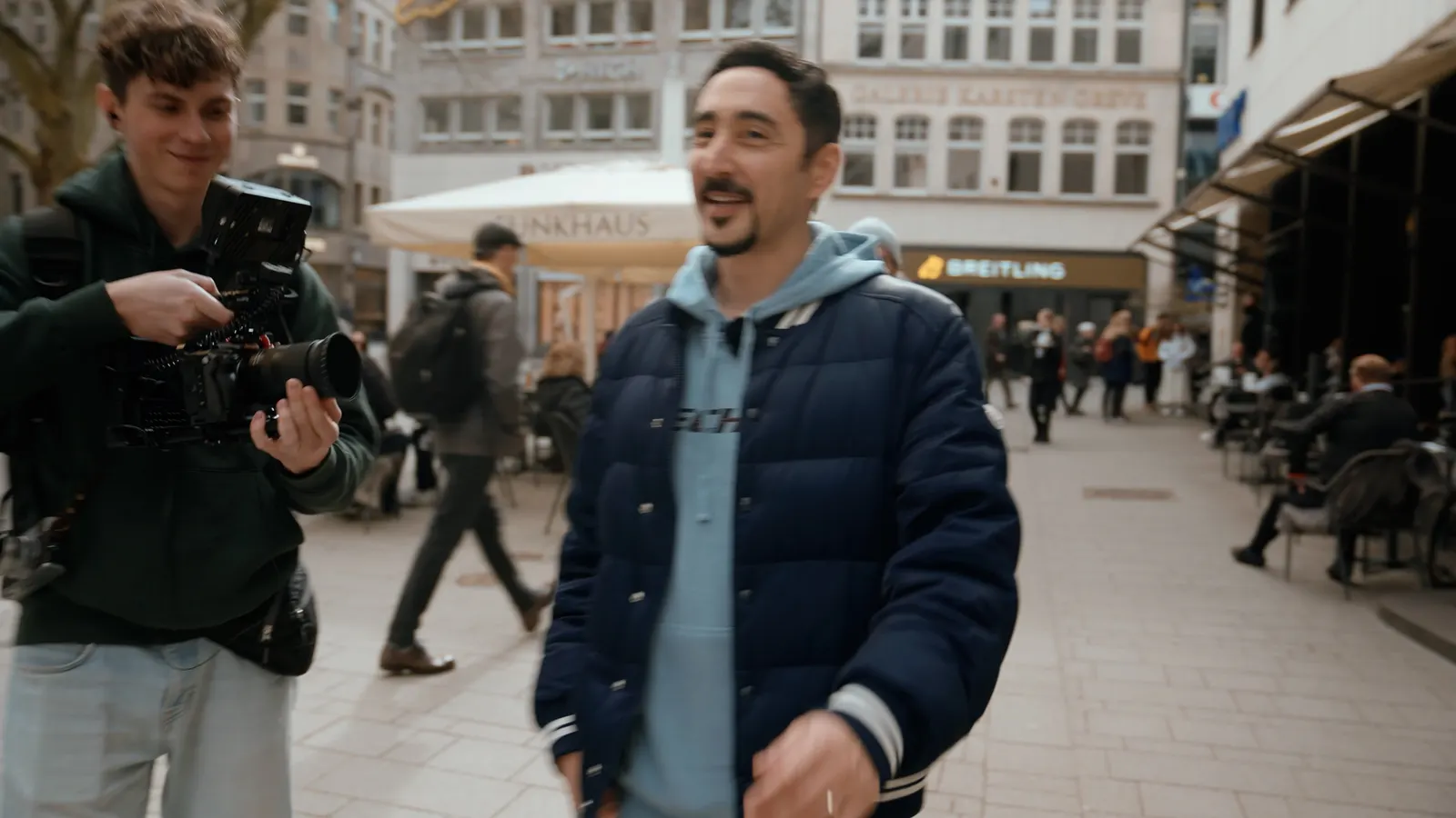 Kameramann filmt zwei Männer in einer Fußgängerzone