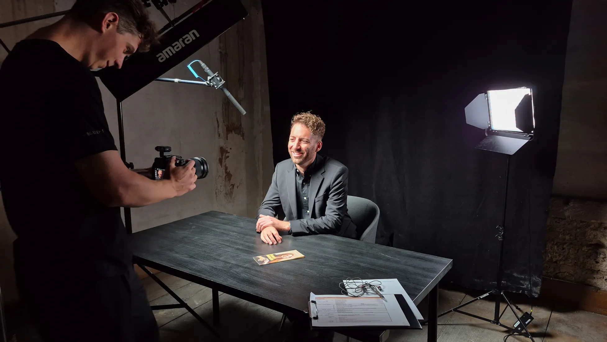 Kameramann filmt einen Mann am Tisch, daneben eine Softbox
