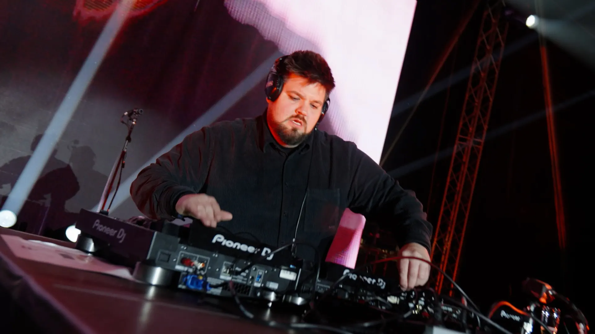 DJ mit Kopfhörern am Mischpult im roten Licht